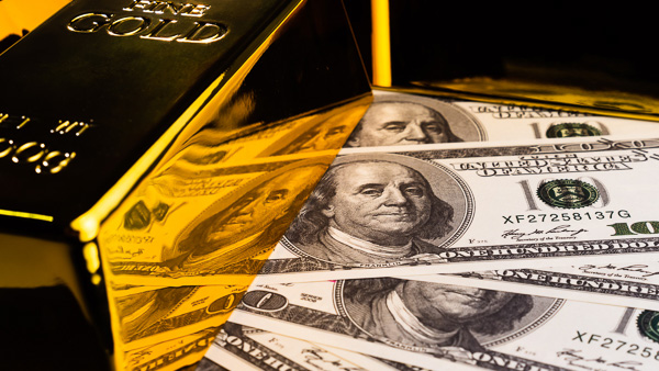 Image: A gold bar sitting on U.S. dollar bills.